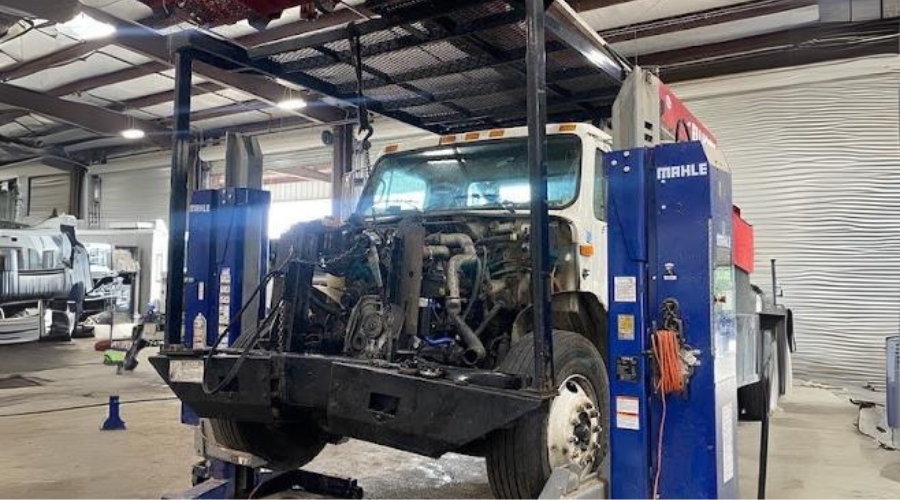 The importance of diesel truck maintenance in Many, LA at Consolidated Truck Parts & Service. Image of electric fleet commercial truck partially lifted with hood completely off for major repairs in the shop.