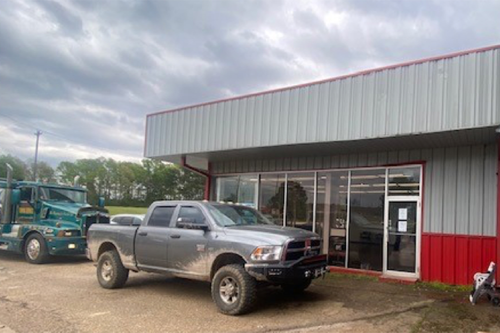 Which is Better: 5.9L or 6.7L Cummins Diesel Engines? With Consolidated Truck Parts in Alexandria, LA. Image of gray Dodge cummins pickup truck parked outside of gray and red metal shop in front of office door.