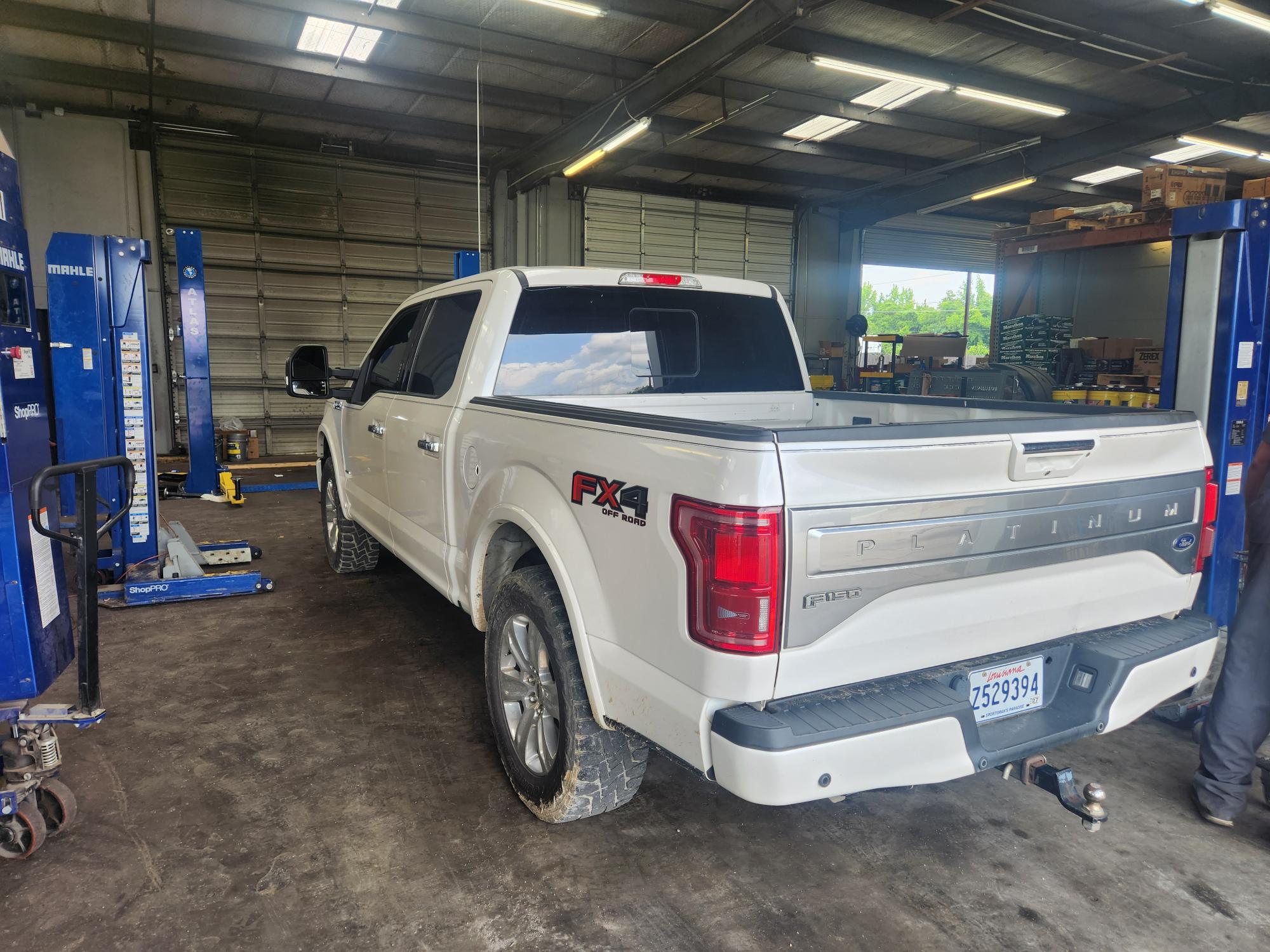 Truck maintenance in Alexandria, LA. with Consolidated Truck Parts & Service. Image of white Ford F 250 in the shop bay getting prepped for fall maintenance.