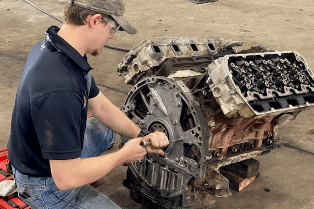 diesel mechanic, diesel repair in Lafayette, LA at Consolidated Truck Parts & Service. Mechanic working on a dismantled engine block, performing maintenance and repairs.