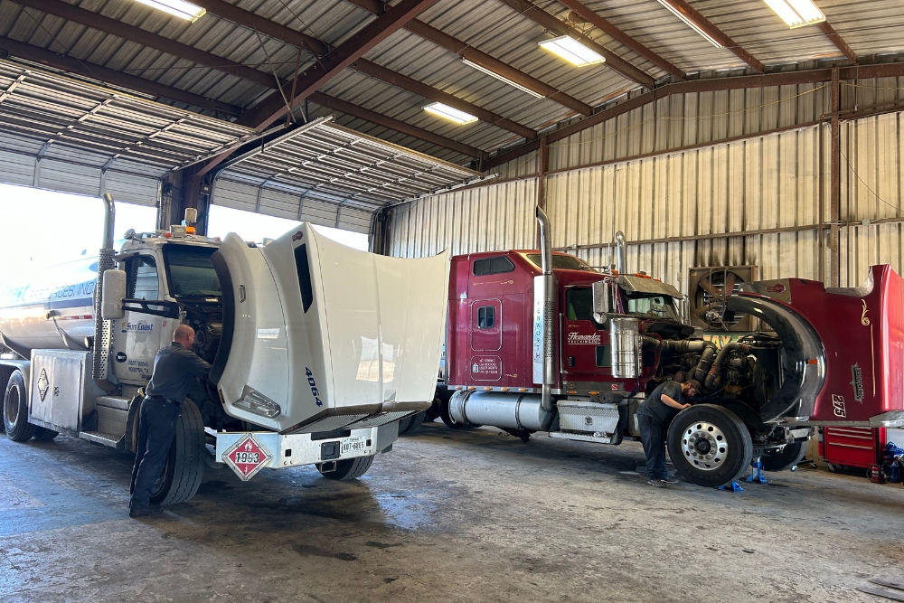 DOT Inspection in Lafayette LA At Consolidated Truck. Two Class 8 commercial trucks inside an auto repair shop during a DOT inspection.